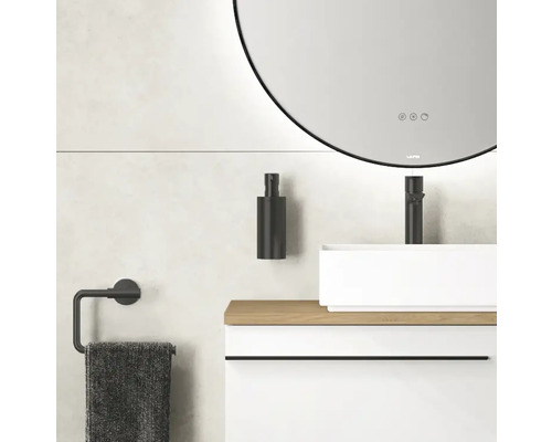 Badezimmer mit rundem Spiegel, Waschbecken, Armatur, Seifenspender und Handtuchhalter