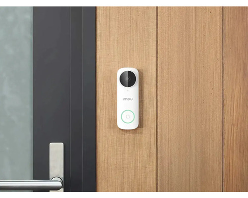 Weiße Imou Video-Türsprechanlage mit Kamera und Klingeltaste an einer hellen Holzfassade neben einer modernen dunklen Tür mit Metallgriff.