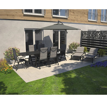 Gartenszene mit Esstisch, Stühlen, Sonnenschirm und Sonnenliegen auf einer Terrasse