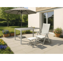 Gartenszene mit Tisch, Stuhl, Fußhocker und Sonnenschirm auf einer Terrasse