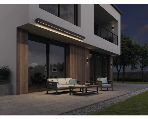 Moderne Hausfassade mit beleuchteter Markise, Gartenmöbeln und Terrasse