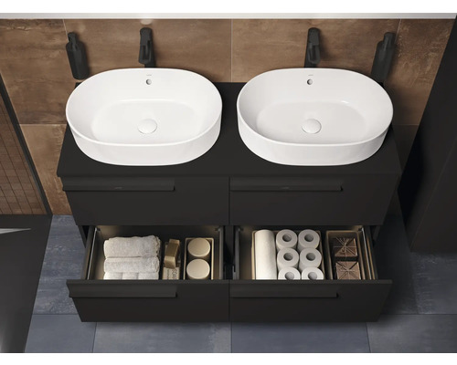 Badezimmer mit Waschbecken, Unterschrank, Armatur, Handtüchern und Badutensilien.