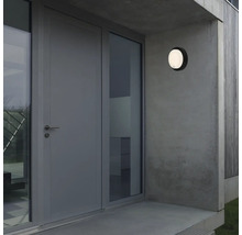 Außenansicht eines Hauses mit Haustür, Fenster und runder Außenleuchte an der Wand