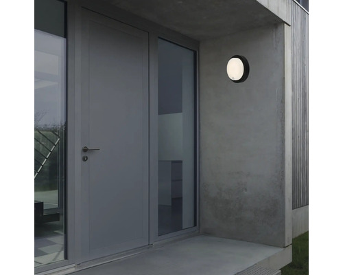 Außenansicht eines Hauses mit Haustür, Fenster und runder Außenleuchte an der Wand