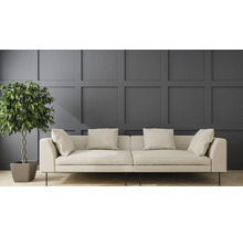 Helles Sofa mit Kissen und Zimmerpflanze vor einer Wandpaneele