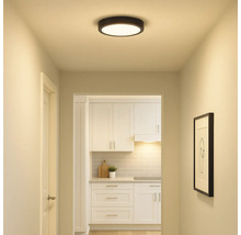 Flur mit runder Deckenleuchte und Blick in eine Küche mit weißen Möbeln