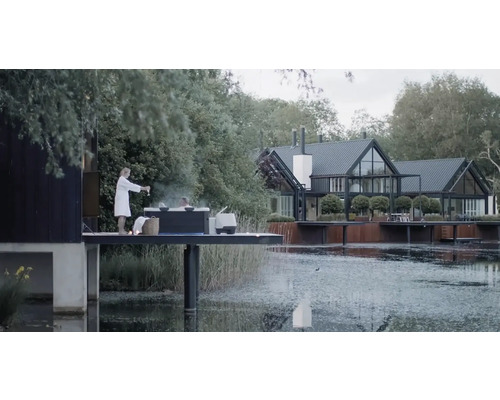 Szene mit einem Whirlpool auf einer Plattform am See und einem Haus im Hintergrund