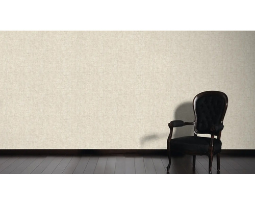 Helle Wand mit Textiltapete und schwarzem Sessel auf dunklem Holzboden.