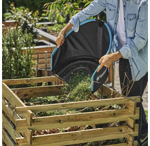 Eine Person leert einen Laubsack von Gardena in einen Holzkohlebehälter im Garten.