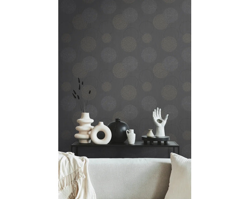 Dekoratives Wohnzimmer mit gemusterter Tapete, Couch und verschiedenen Vasen auf einem schwarzen Tisch