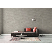 Wohnzimmer mit Sofa, Teppich, Tisch und Stehlampe vor einer strukturierten Tapete.