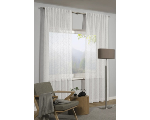 Szene mit transparenten Vorhängen vor einem Fenster, einem Sessel, einem Beistelltisch und einer Stehlampe