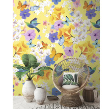 Dekoratives Interieur mit gelber Tapete, verziert mit Blumen, Schmetterlingen und Vögeln, ergänzt durch Korbsessel und Zimmerpflanzen