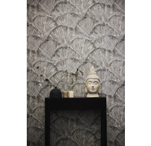 Tapete mit Fächermuster, Buddha-Statue, Vase und Kerzen auf einem schwarzen Tisch