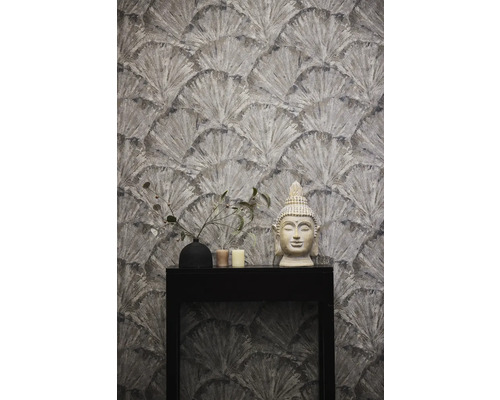 Tapete mit Fächermuster, Buddha-Statue, Vase und Kerzen auf einem schwarzen Tisch