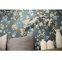 Detailaufnahme einer Wand mit Blumentapete, Kissen und dekorativen Vasen.