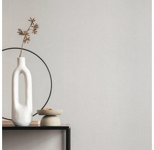 Nahaufnahme einer Wand mit Tapete, einer Vase und dekorativen Accessoires auf einem Tisch.