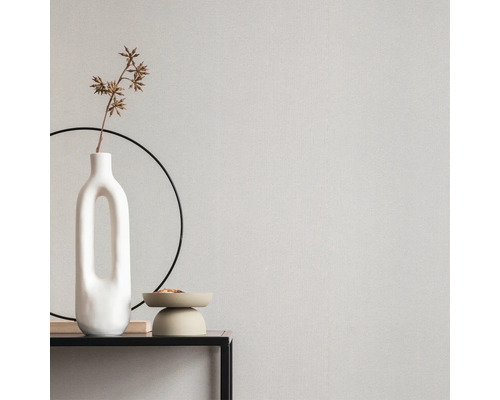 Nahaufnahme einer Wand mit Tapete, einer Vase und dekorativen Accessoires auf einem Tisch.