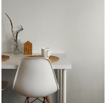 Weißer Tisch mit Dekorationen, darunter ein Glas, ein Holzhaus und eine Tasse