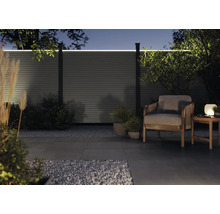 Moderne Gartenszene mit beleuchtetem Zaun, Sessel und Beistelltisch bei Nacht