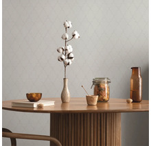 Dekorativer Tisch mit Baumwollzweig, Glasbehälter und Geschirr vor einer gemusterten Wand