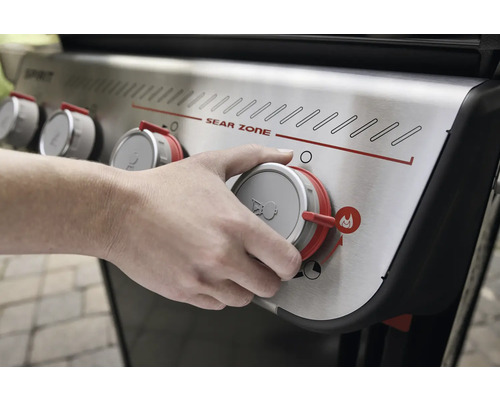 Person bedient Drehknopf am Gasgrill