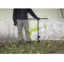 Person mit Erdlochbohrer im Garten