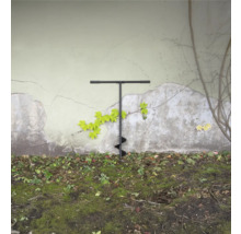 Erdlochbohrer im Garten vor einer Wand