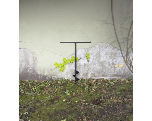 Erdlochbohrer im Garten vor einer Wand