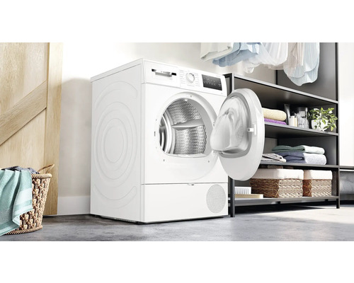 Weißer Wäschetrockner mit geöffneter Tür und Wäschekorb im Waschraum