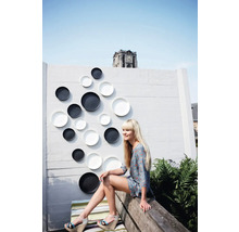 Dekorative Wand mit Ziertellern im Außenbereich mit Frau auf einer Bank