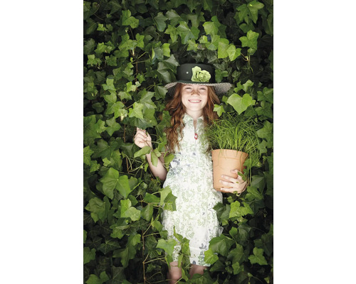 Mädchen mit Hut und Pflanze im Topf, umgeben von Efeu