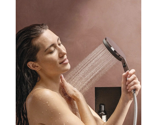 Eine Frau benutzt eine Handbrause unter der Dusche.