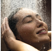 Frau genießt Dusche mit geschlossenen Augen