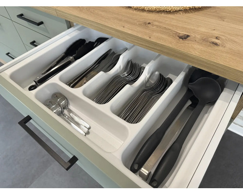 Geöffnete Schublade mit Besteckkasten und verschiedenen Küchenutensilien wie Zange, Messern, Gabeln, Löffeln und Schöpfkellen.