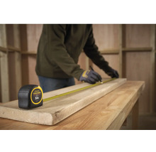 Handwerker misst ein Holzbrett mit einem Stanley Fatmax Rollbandmass, Länge 5 Meter.