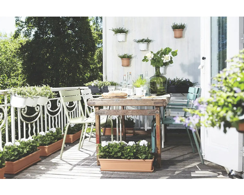 Helle und einladende Terrasse mit Esstisch, Stühlen und Bepflanzung in Töpfen und Kästen