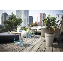 Dachterrasse mit Lounge-Möbeln, Beistelltisch und Topfpflanzen vor einer Stadtkulisse