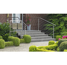 Eingangsbereich eines Hauses mit Treppe, Edelstahlgeländer und Briefkästen vor einer Ziegelwand.