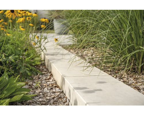 Gartenweg aus Betonsteinen mit Blumen und Ziergräsern