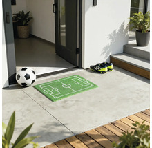 Fußball vor einer Haustür mit Fußballfeld Fußmatte und Fußballschuhen.