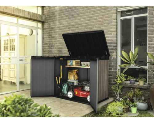 Geöffneter Geräteschrank mit Gartengeräten und Rasenmäher