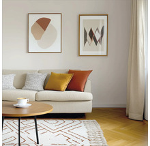 Wohnzimmer mit Sofa, Kissen, Couchtisch, Teppich und zwei gerahmten Bildern an der Wand