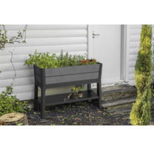 Hochbeet aus Kunststoff mit Ablage vor einer Hauswand