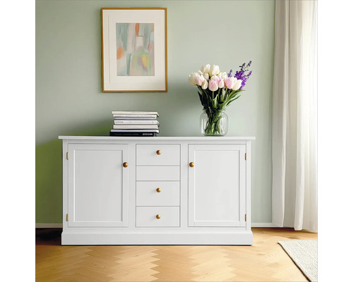 Weißes Sideboard mit Schubladen und Schranktüren, Bücherstapel, Blumenstrauß und gerahmtem Bild