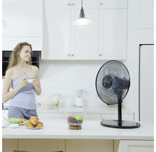Tischventilator in einer hellen Küche mit einer Frau, die eine Tasse hält