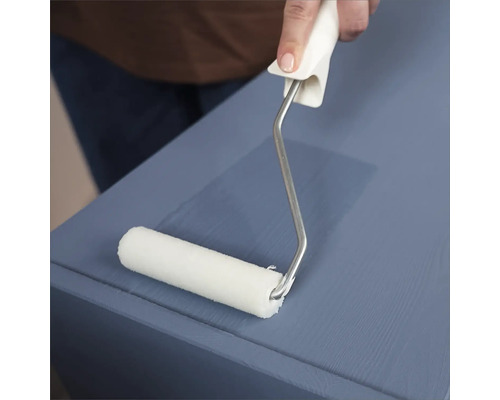 Eine Person streicht mit einer Farbwalze eine Oberfläche.