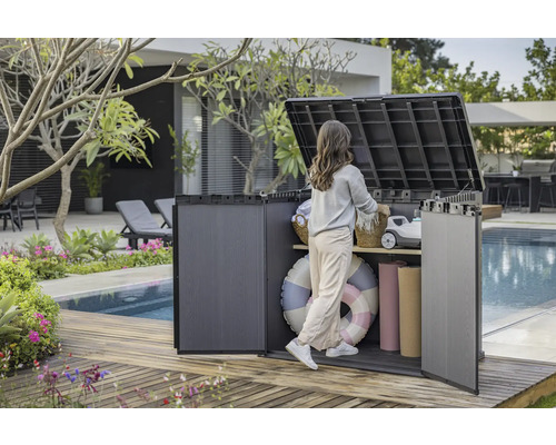 Gartenszene mit einer Frau, die einen Kunststoff-Geräteschrank am Pool benutzt, um Gegenstände zu verstauen