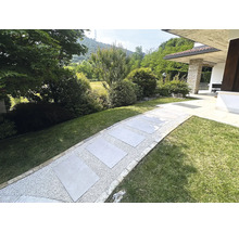 Gartenweg mit Steinplatten und Kies zwischen Grünflächen
