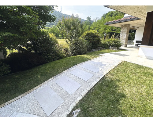 Gartenweg mit Steinplatten und Kies zwischen Grünflächen